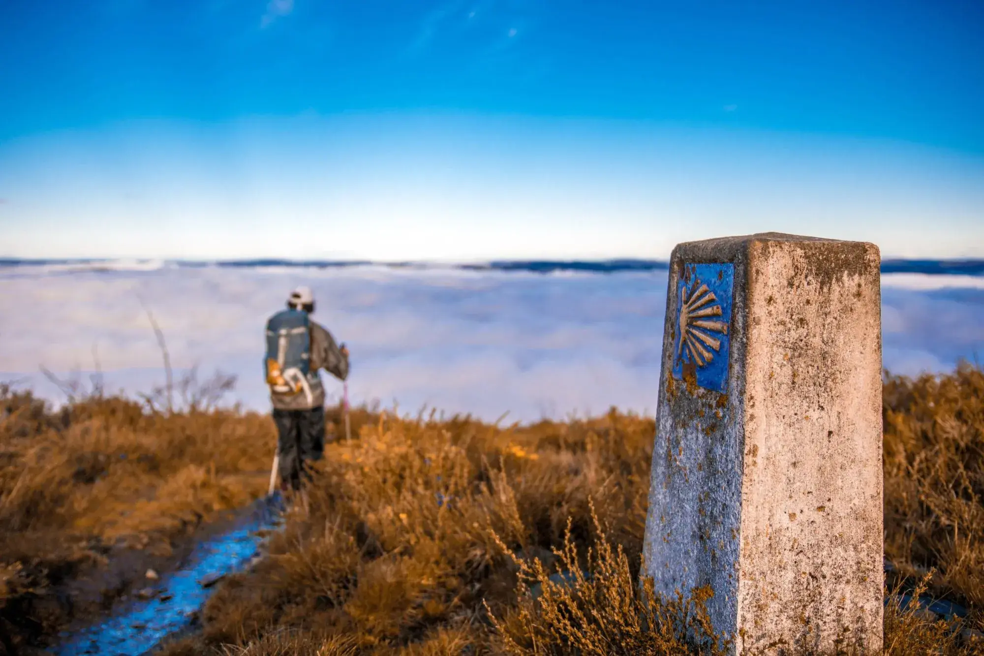 pilgrim-walking-above-clouds-on-camino-primitivo-scaled