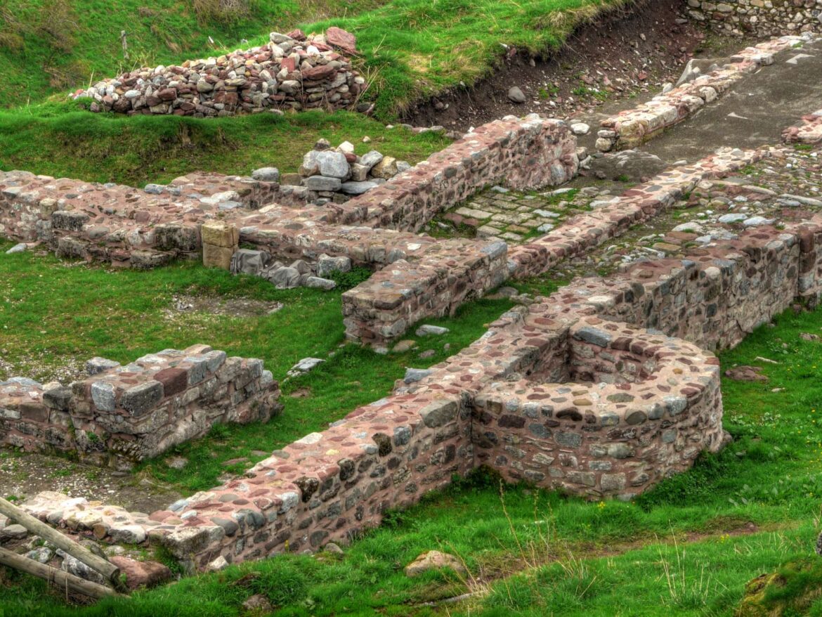 Ruined stone walls form terraces along a grassy hillside.