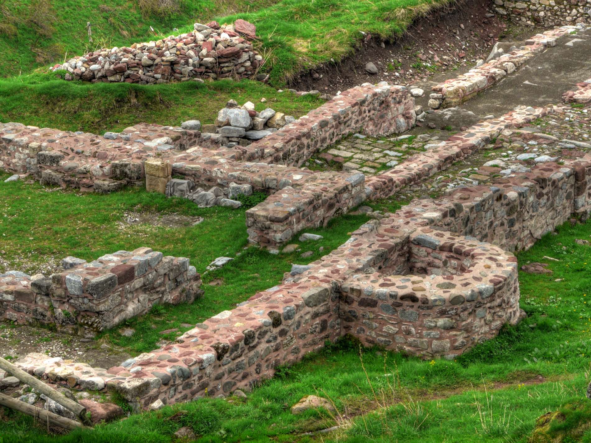 Ruined stone walls form terraces along a grassy hillside.