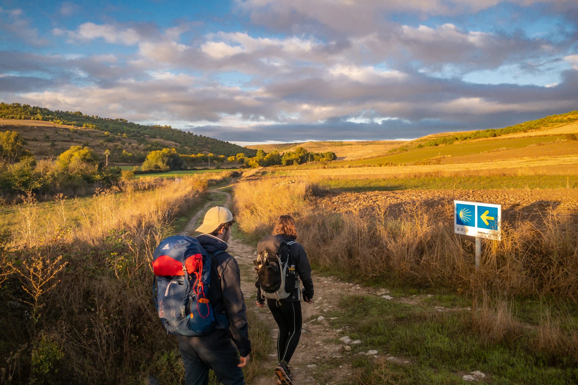 two-pilgrims-walking-at-sunrise-on-the-way-of-st-james-camino-de-santiago-pilgrimage-trail
