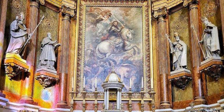Ornate church altar with a central painting of a rider on a white horse, flanked by statues and gilded columns.