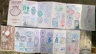 Open passport-style booklet filled with colorful stamp-like illustrations, laid flat on a surface.