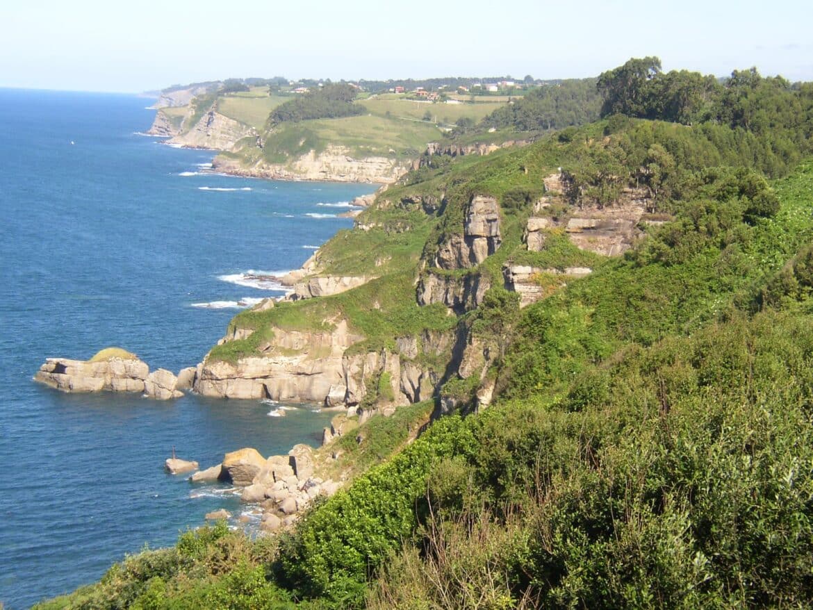 Cliffside coastline with green hills, rocky cliffs, and the blue ocean along the shore.