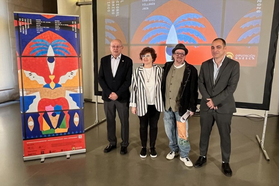 Four people pose for a photo at an art event, standing in front of colorful banners with abstract designs.