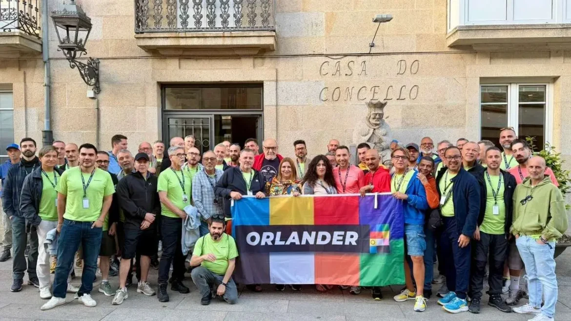 Large group of people posing outdoors behind a colorful banner that reads 'ORLANDER' in front of a stone city hall building (Casa do Concello).