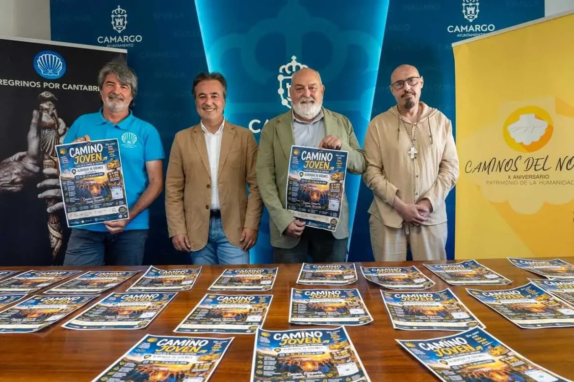 Four men stand behind a table covered with Camino Joven flyers; blue banners and a yellow banner appear in the background.