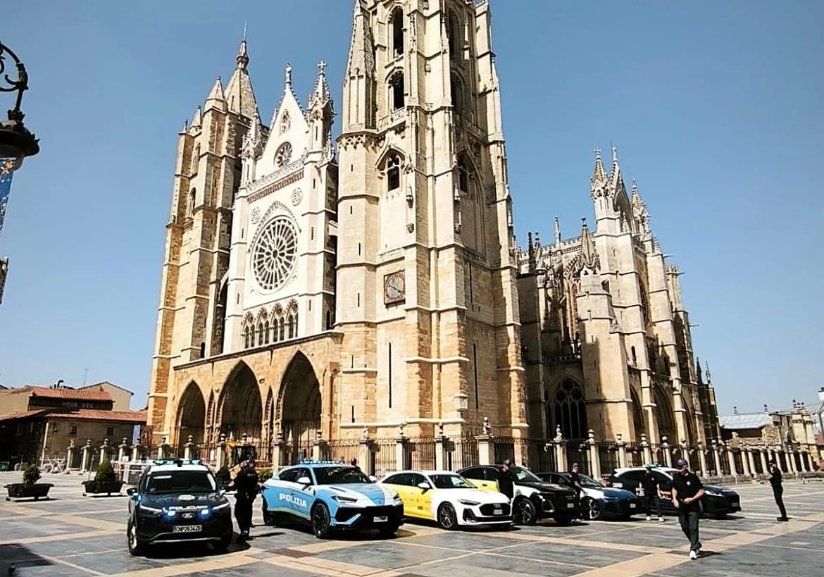 Gothic cathedral with a large rose window and arched entry, police cars parked in front and officers nearby.