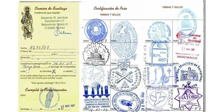 A page with multiple blue and purple travel stamps, including a yellow certificate on the left and round stamps from various towns on the right, suggesting a Camino de Santiago journey.