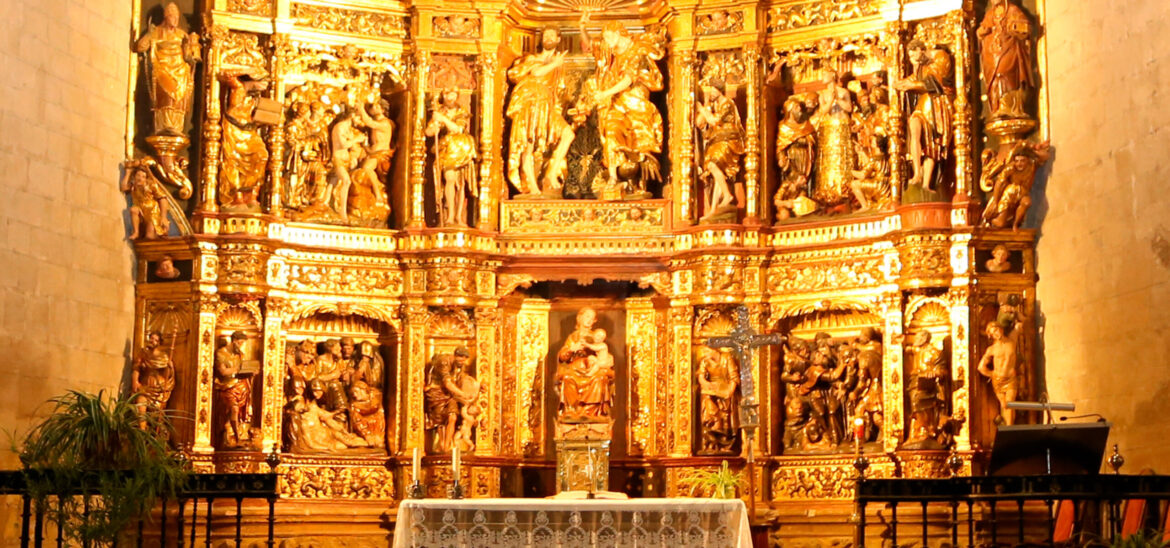 Ornate gold-leaf altar with many saint statues in a warmly lit church interior