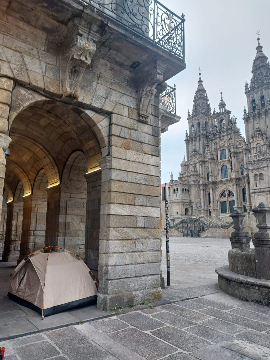 Tent set up under a stone archway of a historic building, with ornate Gothic cathedral towers in the background.