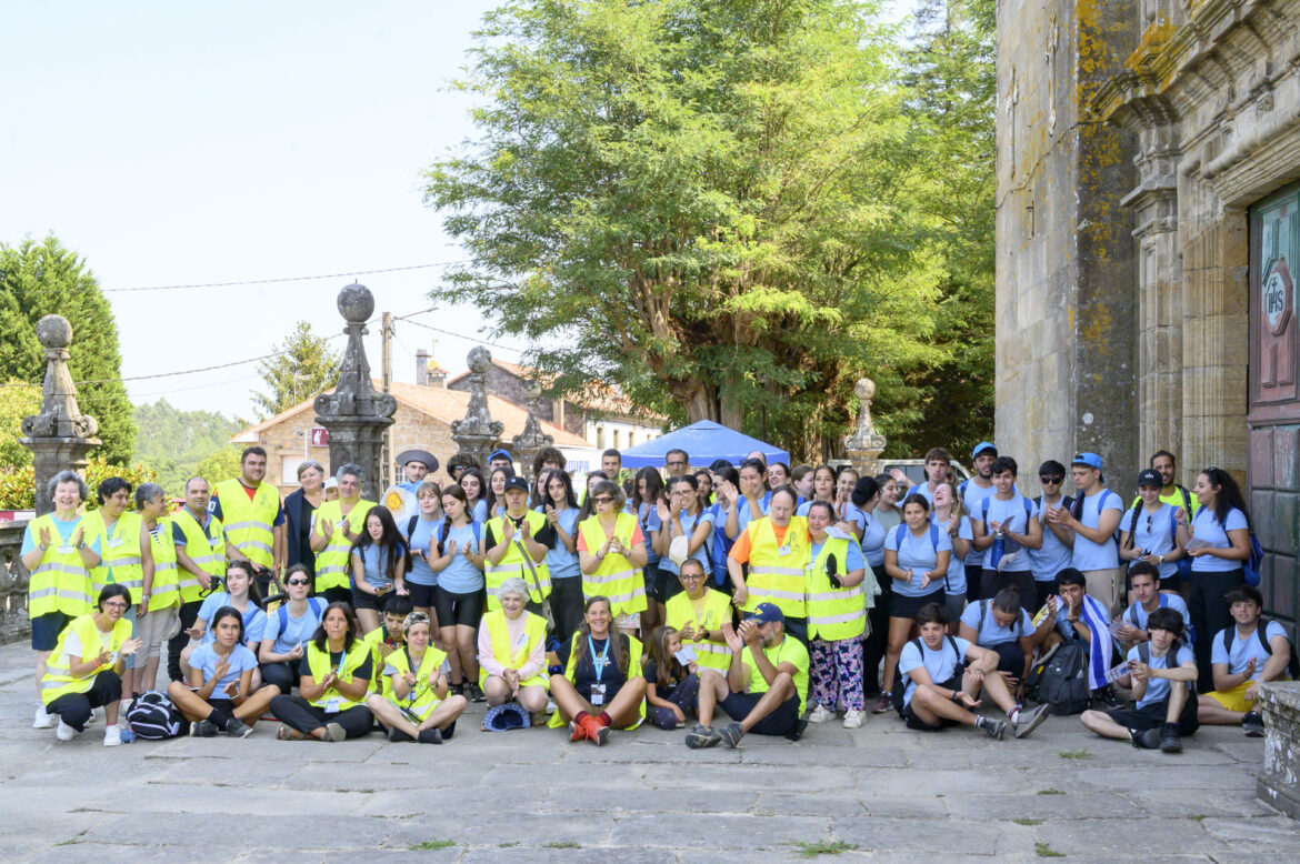 Group of volunteers in yellow safety vests posing for a photo in front of a historic stone building.