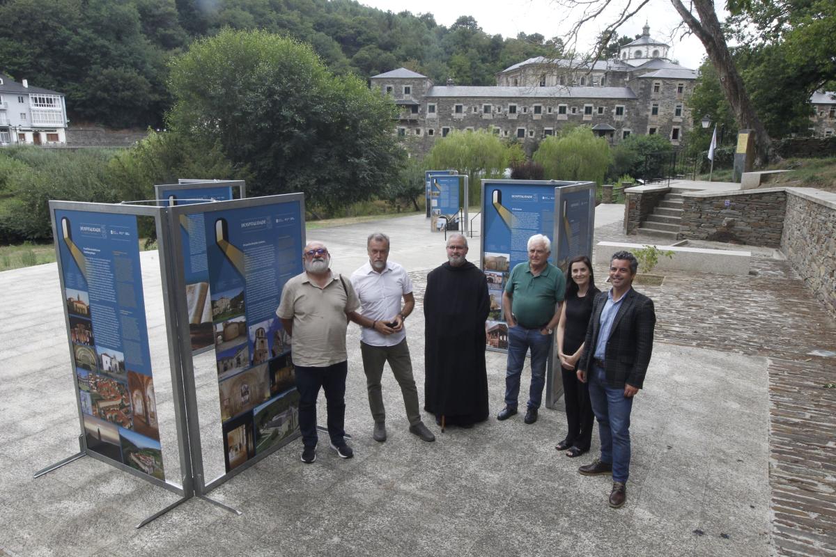 Six adults stand beside blue information panels at an outdoor historical site exhibit.