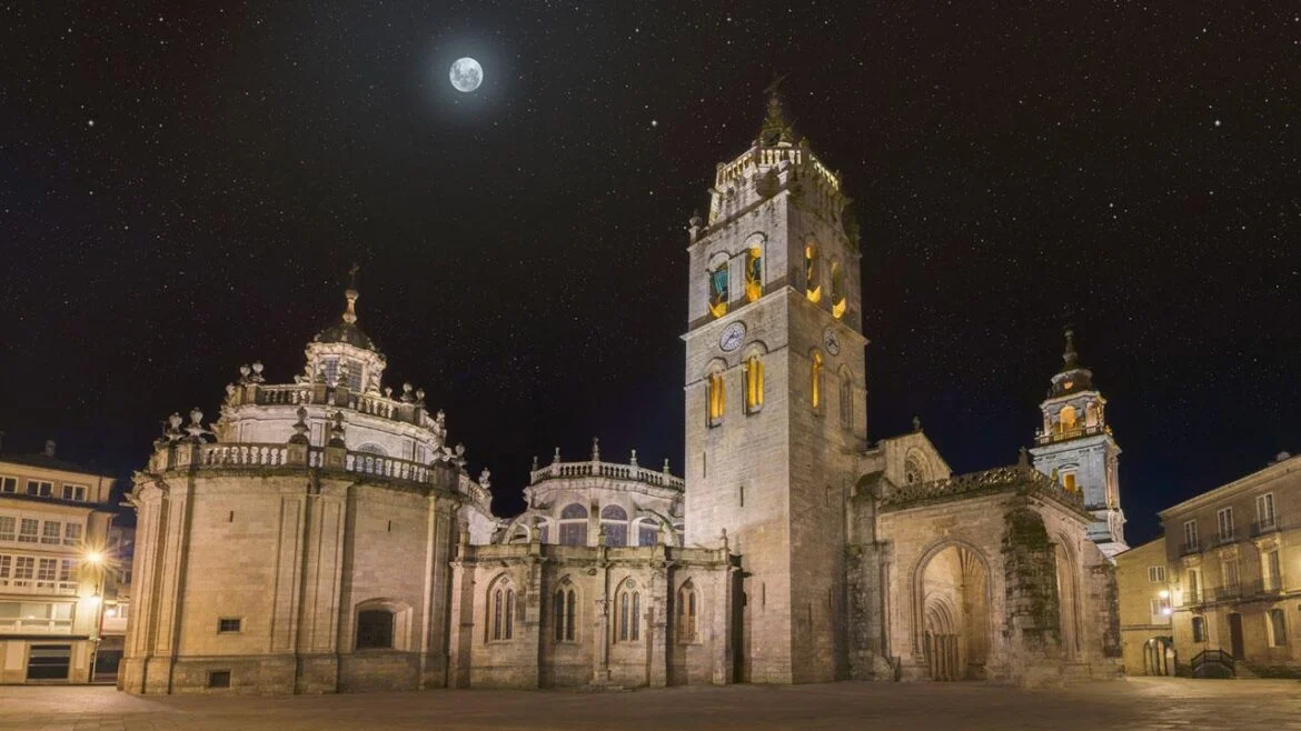Moonlit historic cathedral complex s tall clock tower in quiet square, starry night sky i visible moon above.