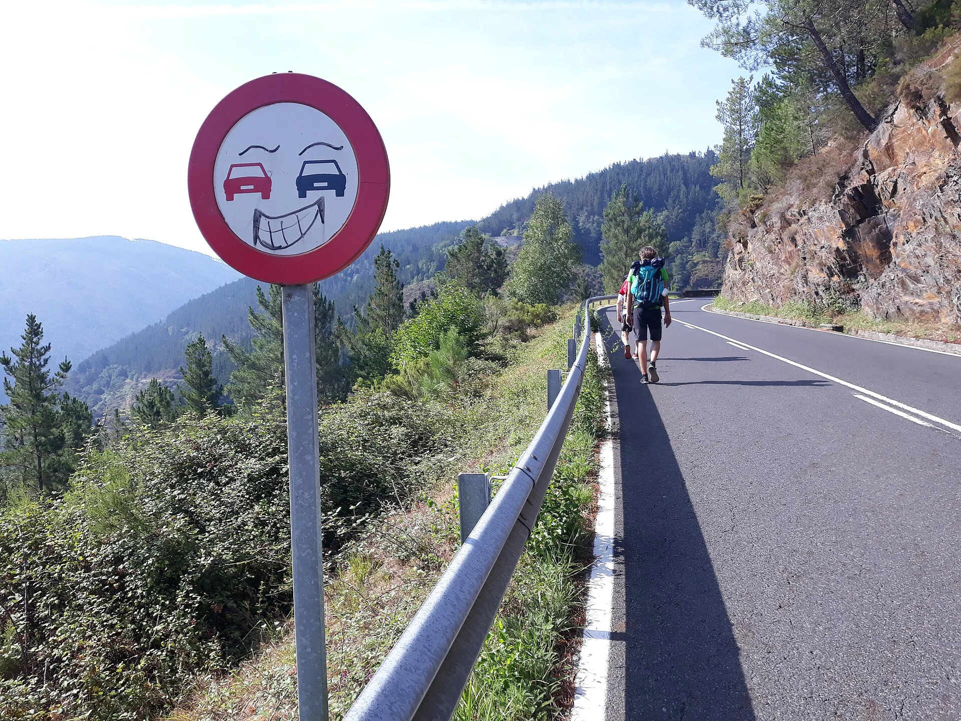 Pilgrim next to a mountain road with danger sign