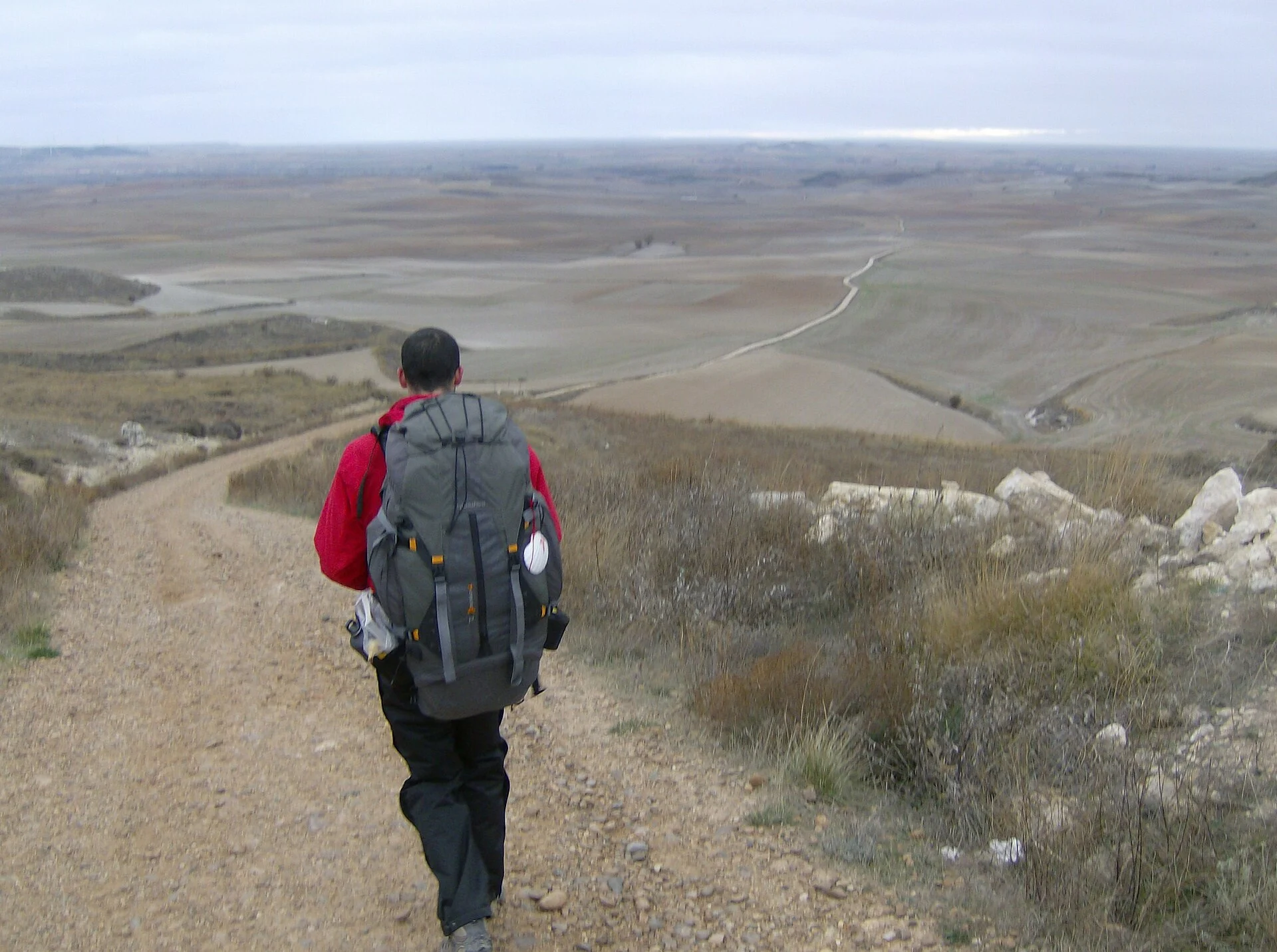 Pèlerin avec sac à dos marchant le long d'une piste du Camino de Santiago